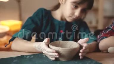 孩子正在做一盘粘土。 陶艺课。 小女孩在粘土邮票上做图案